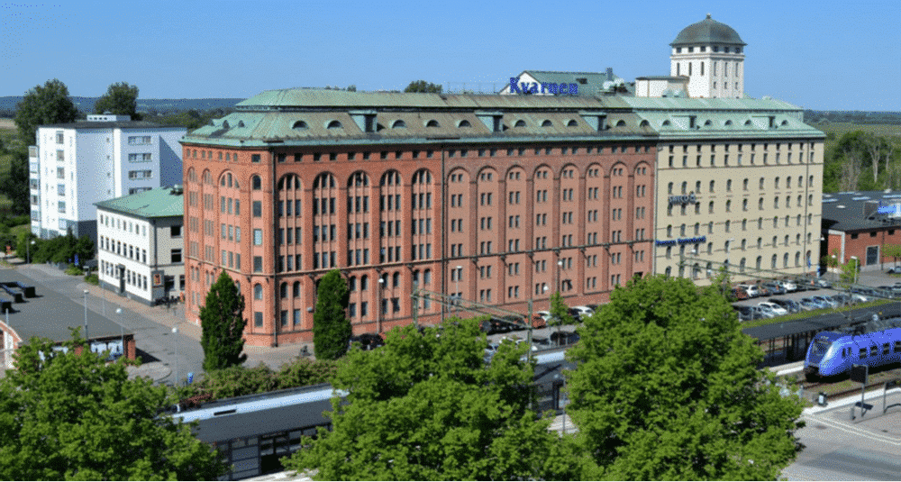 Historisk byggnad i centrala Kristianstad, omgiven av grönska och med tågstation i närheten